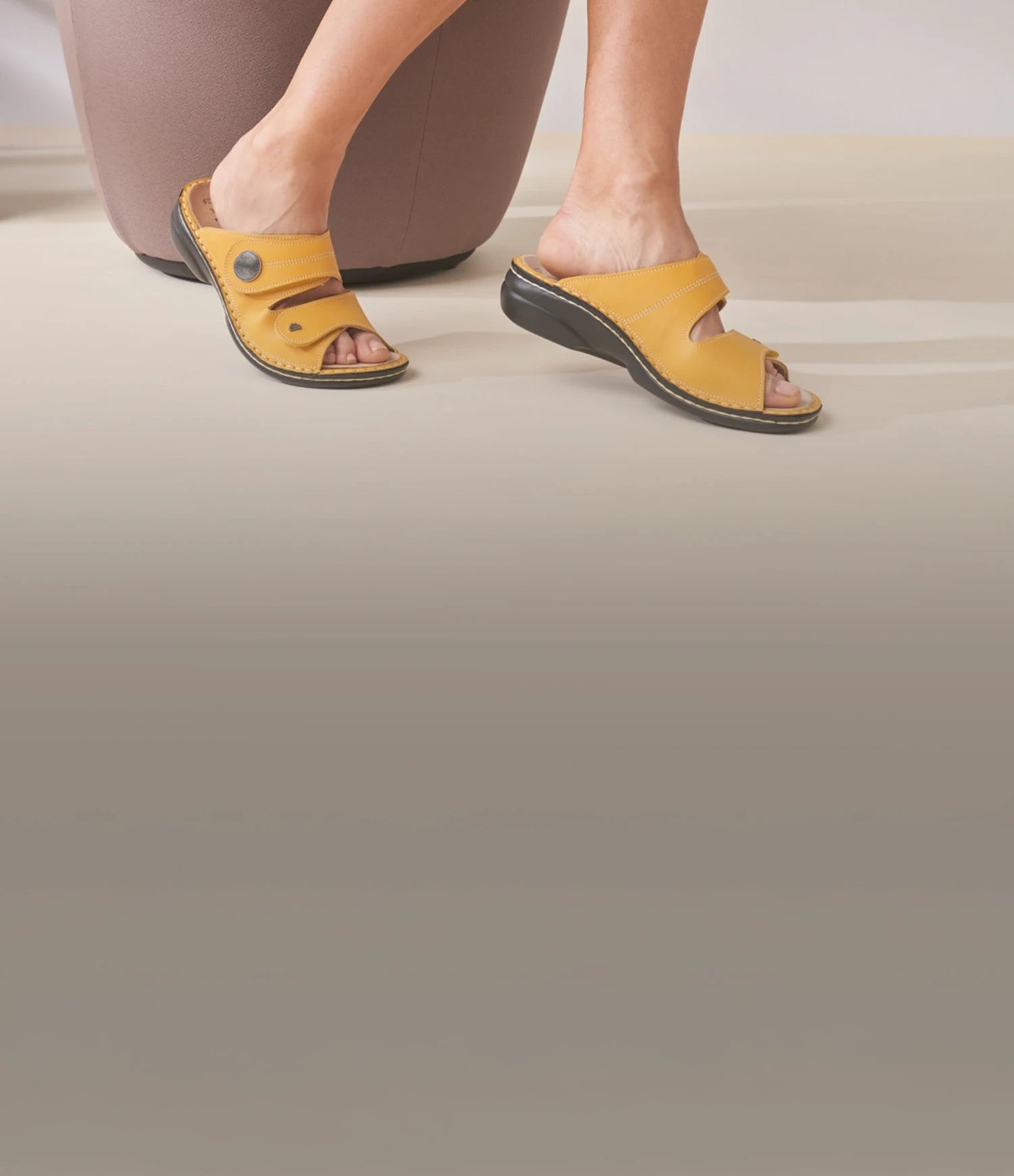 Primo piano di Sansibar gialle ciabatte finncomfort con plantare estraibile in vista laterale indossate da donna seduta su poltrona