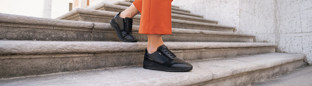 primo piano di donna che scende le scale in città indossando mori scarpe finncomfort nere