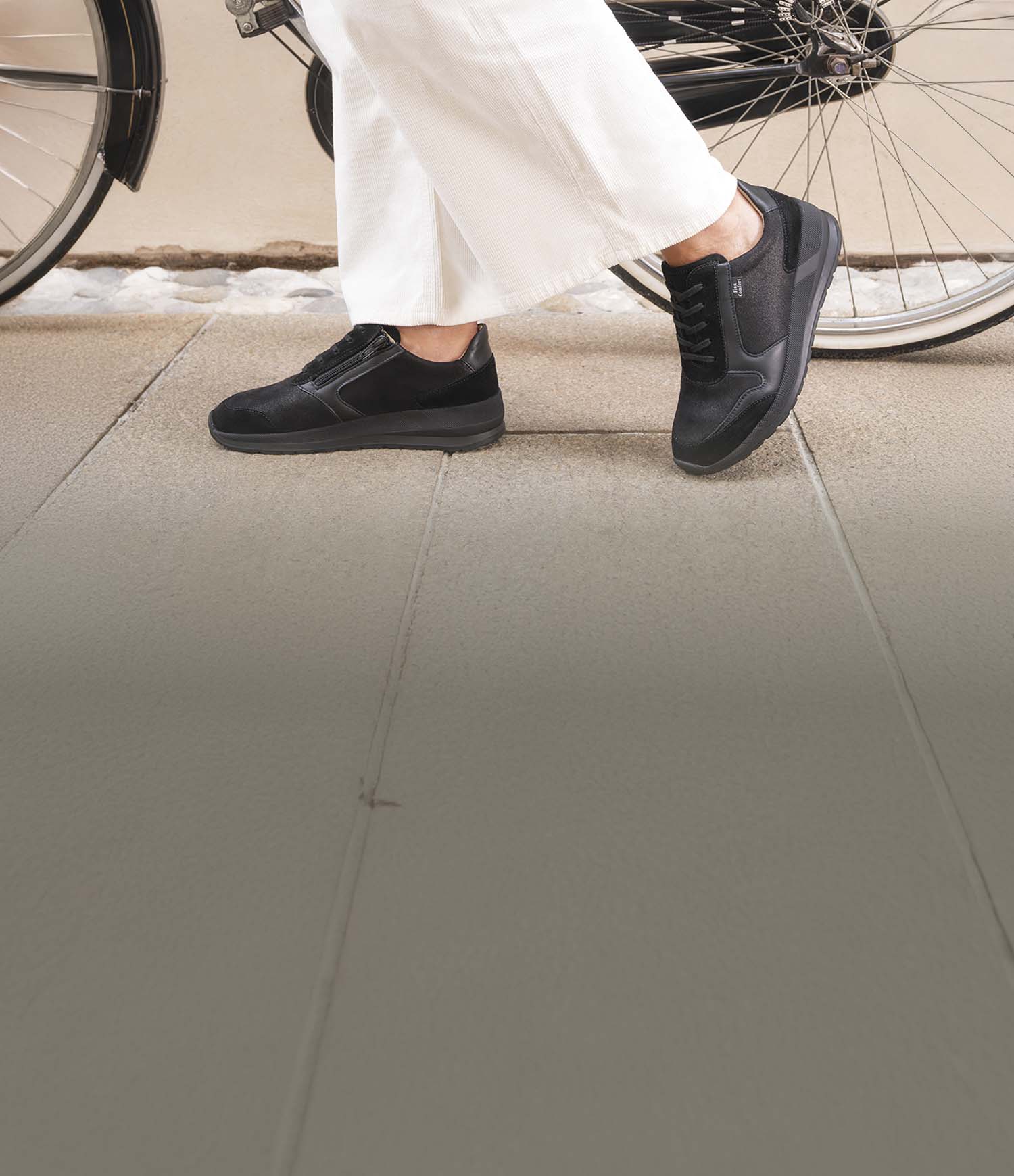 Primo piano di scarpe finncomfort mori nere indossate da signora che  bicicletta nera a fianco di una bicicletta