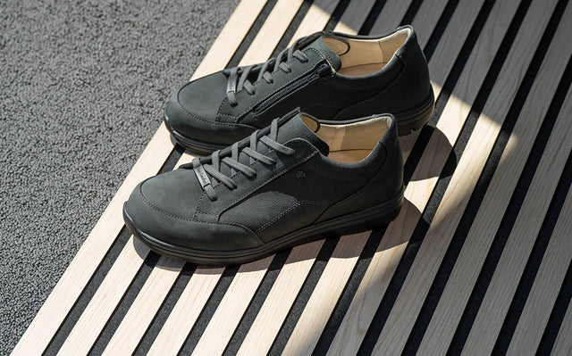primo piano di scarpe finncomfort nere appoggiate su una panca in legno moderna