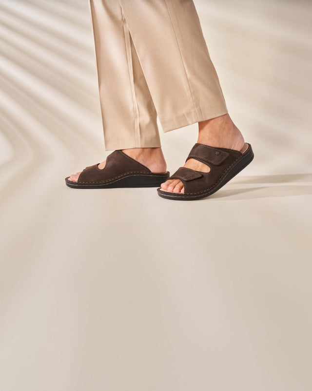 Ciabatte ortopediche da uomo FinnComfort modello RIAD in pelle marrone scuro, indossate con pantaloni beige, comfort e stile per il benessere quotidiano