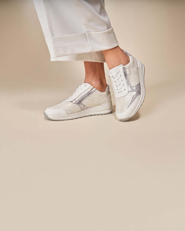 Scarpe sneakers ortopediche da donna FinnComfort modello Mori in pelle bianca traforata con dettagli argento, indossate con pantaloni bianchi, comfort e stile per camminare ogni giorno.
