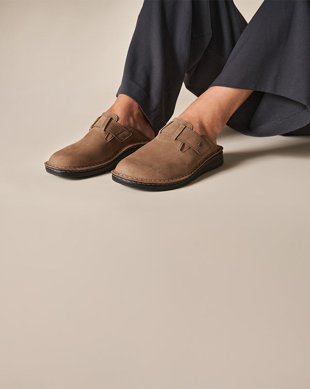 Primo piano di sabot Finncomfort da uomo Petare barrel indossato da uomo con pantaloni blu.
